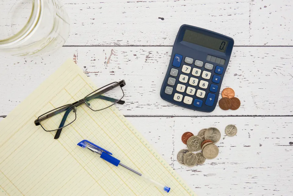 Bills, a calculator and reading glasses on a table