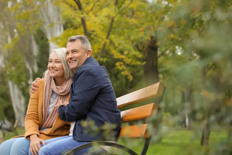 An older couple sitting together on a park bench