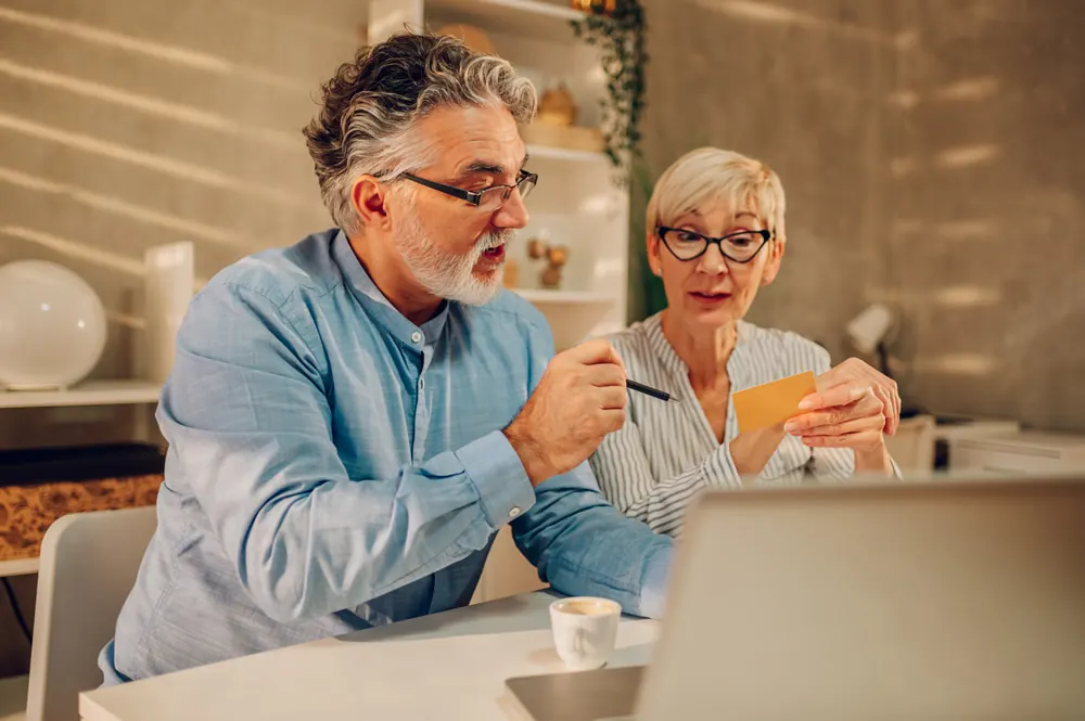 An older man and woman reading a letter at home
