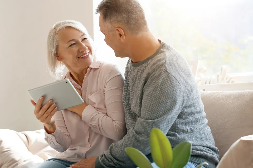 An older couple looking at a tablet on the couch