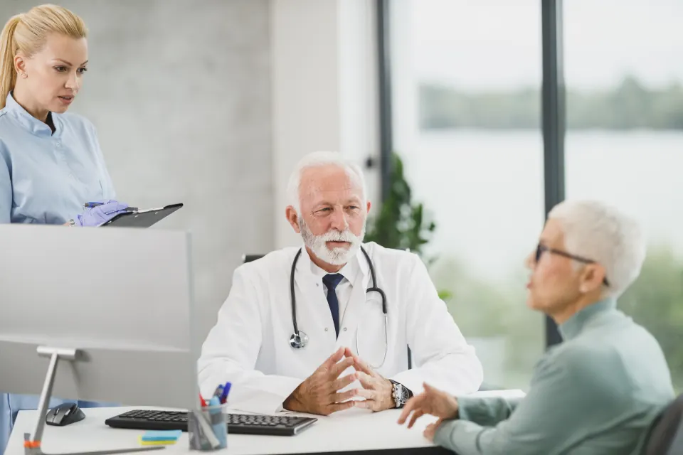 A doctor and nurse talking with an older woman
