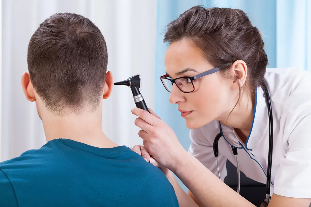 A doctor examining a young man’s ear