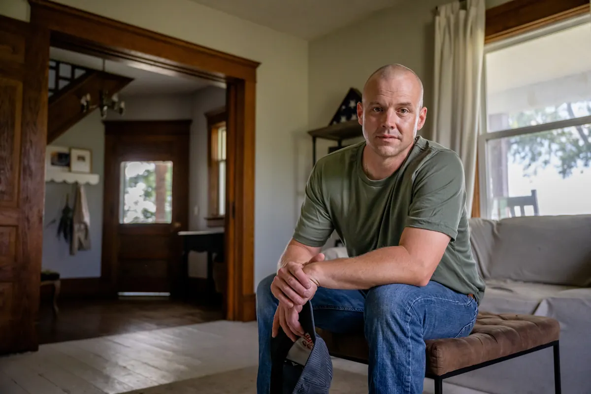 A man sitting on the arm of a couch at home