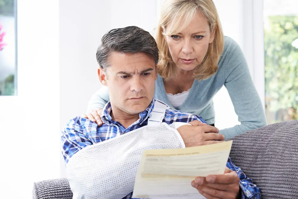 A man in a sling reading paperwork with his partner