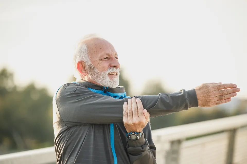 An older man stretching his arms outdoors
