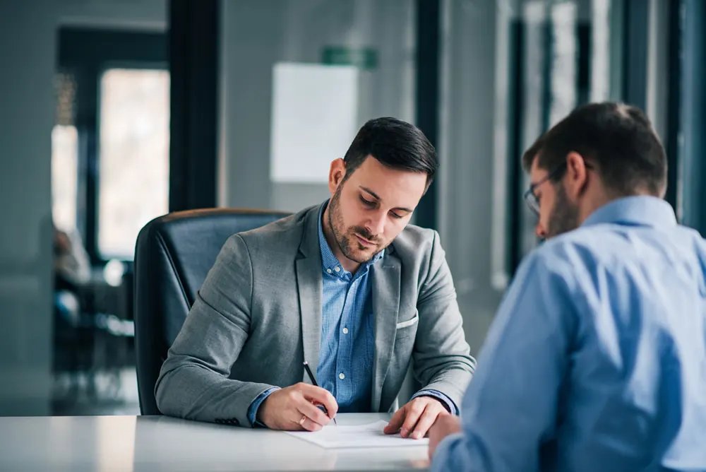 Two men reviewing and signing a document
