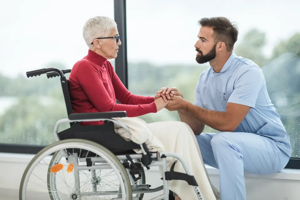 A nurse talking with an older woman in a wheelchair