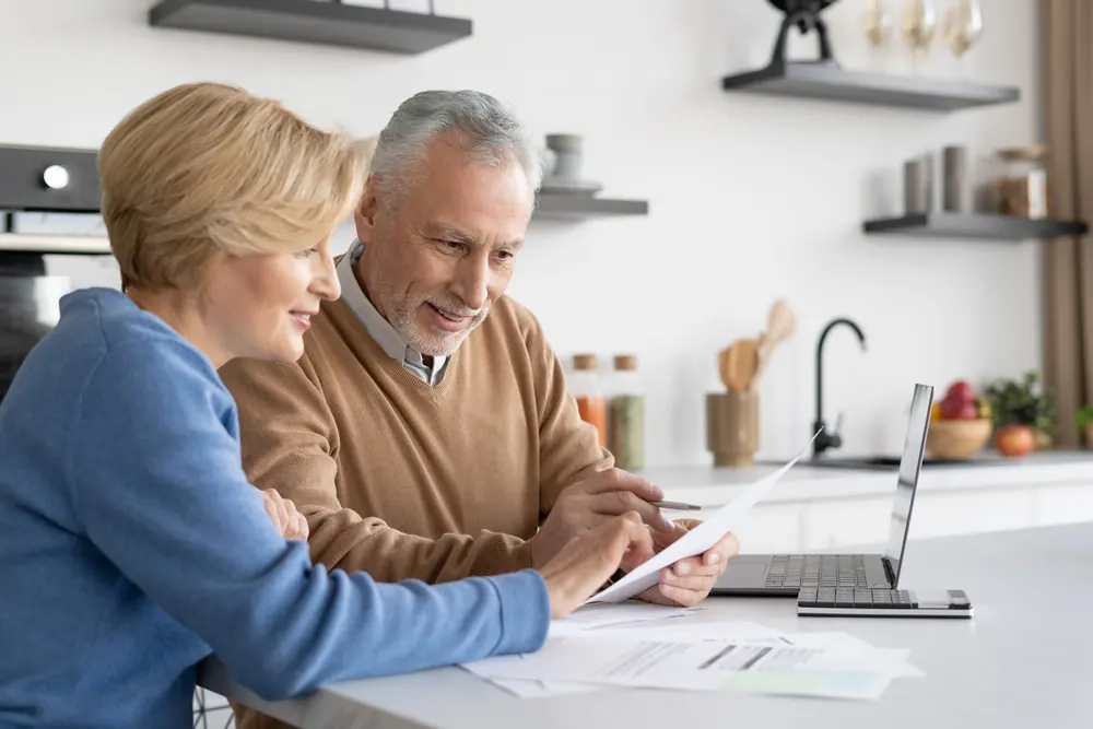 An older couple reading papers in the kitchen