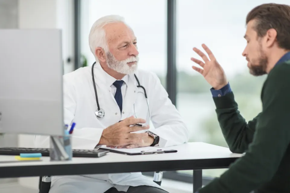 A doctor listening to a patient across a desk