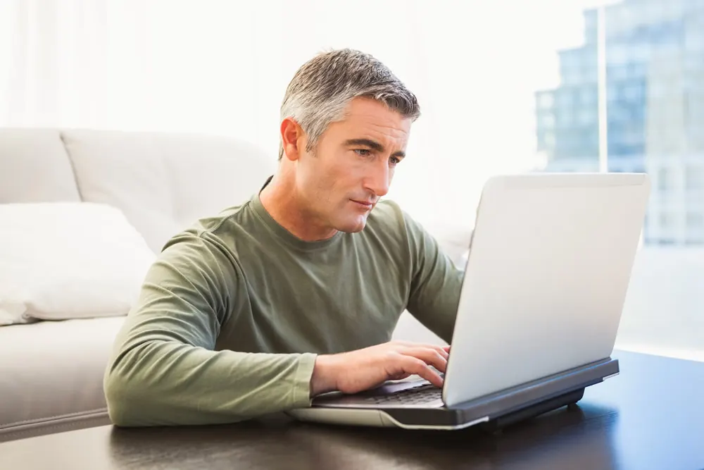 An older man using a laptop on the couch