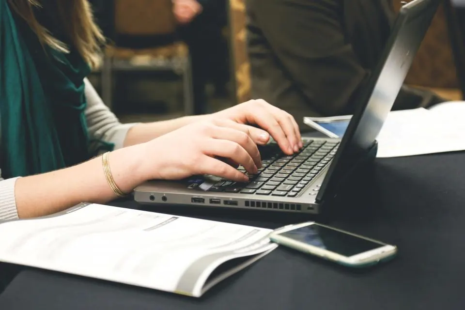 Hands typing on a laptop