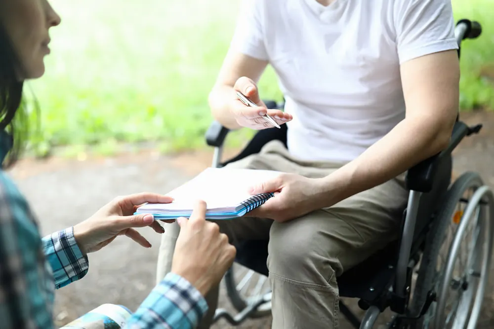 A man in a wheelchair going through a document with someone